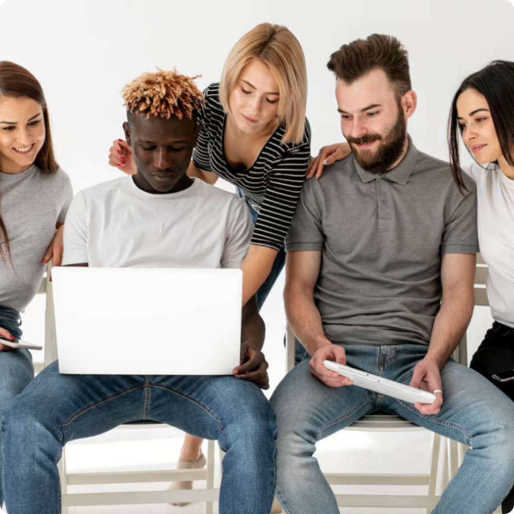 Nesta imagem vemos um grupo de 5 pessoas, 3 mulheres brancas e cis e dois homens cis, um negro e um branco, segurando um computador